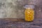 Macaroni in a glass jar placed on the old wood table on the table, selective focus