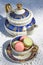 Macarons biscuits with ceramic blue and golden teapot and cup and white tablecloth