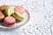 Macarons biscuits with ceramic saucer and white embroidered tablecloth