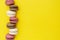 Macarons cakes. Fashion or feminine background delicious macaroons in row on yellow background. Flat lay social media walpaper.