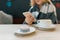 Macaroon in plate, cup of coffee, beautiful blonde girl in woolen blanket with smartphone