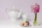 Macaroons and transparent vase with pink hyacinth flowers on porcelain tea pot and cup background.