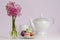 Macaroons and transparent vase with pink hyacinth flowers on porcelain tea pot and cup background.