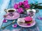 Macaroons and two pink cups of coffee and peony blooming pink roses