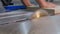 Machine tool with a circular saw and the hands of a joiner close-up. Sawing off the edge on a double thickened chipboard part. Cut