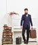 Macho attractive, elegant on strict face carries vintage suitcases. Butler and service concept. Man with beard and