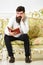 Macho on disgusted face reading book. Scandalous bestseller concept. Man with beard and mustache sits on baroque style