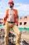 macho foreman. Guy protective helmet stand in front of building made out of red bricks. Builder orange vest helmet