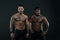 Machos with muscular tattooed torsos look attractive, dark background. Athletes on confident faces with nude muscular