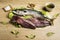 Mackerel fresh fish on lettuce leaves next to bay leaves, a few pieces of lemon, a bowl of oil and some spices on a wooden table