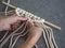 Macrame. Girl weaves macrame. White thread, female hand, grey background, close-up