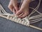 Macrame. Girl weaves macrame. White thread, female hand, grey background, close-up