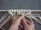 Macrame. Girl weaves macrame. White thread, female hand, grey background, close-up