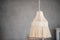 Macrame lamp hangs on gray plain background. Handmade hobby. Decoration in Boho style. Scandinavian