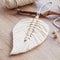 Macrame leaf  in natural color and thread windings lying on a wooden table. Cotton rope decor macrame to make your room more cozy