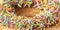 Macro of chocolate colorful donut. Texture donut with pieces of nuts closeup. Banner sweet food