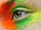 Macro and close-up creative make-up theme: beautiful female eye with orange, green and yellow pigment, retouched photo