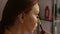 Macro close-up of focused redhead young woman model applying eyeshadow on upper eyelid using soft brush looking to