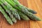 Macro close-up of green asparagus on used kitchen board, horizontally