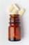 Macro Close up of medicinal or herbal pale yellow tablet spilled and in an amber glass bottle. Top view,