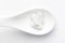 Macro Close up of medicinal or herbal white tablet on a white ceramic spoon. Top view