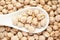 Macro Close-up of Organic chhole chana or Kabuli chana Cicer arietinum or whole white Bengal gram dal on a white ceramic spoon.