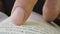 Macro close-up of person reading music publishing book with finger