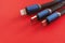 Macro Close-Up of USB-C, Lightning, and Micro USB with Black and Blue Colors Cables on Red Background