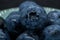 Macro closeup photo of blueberries laying on top of each other in a plate washed with fresh water and with reflection of ambient