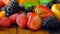 Macro closeup of rotating mixed summer fruit on wooden table.