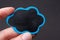 Macro closeup shot of a person`s hand holding a black and blue cloud on a gray background