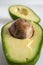 Macro closeup of two half avocados with seed, selective focus, on white wooden table