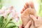 Macro detail of foot massage next to flowers.