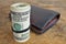 Macro detail of a green roll of American currency USD, American dollars with 100 dollars bank note next to a leather wallet as a