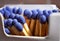 Macro detail of safety match sticks with blue heads in the paper match box (matchbox) in shape of typical cigarette box