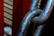 Macro detail view of heavy black steel chain links with brown blurred background.