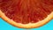 Macro details of a blood orange slice rotating top view on light blue background.Macro food.Looped rotation.Healthy eating concept