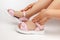 macro details pink children& x27;s sandals on the girl& x27;s feet of a child sitting on a white poured background