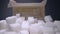 Macro dolly shot of gliding through sugar cubes next into carton box on wooden table. Unhealthy food sweetener, sweet crystal
