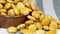 Macro of an earthenware bowl full to the brim with salted lupin beans, on top of a stripped gray cloth towel.