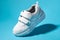 macro flying white child sneakers with velcro fasteners isolated on a blue background with hard light