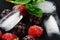 Macro frozen raspberry, blackberry, strawberries mint leaves, pieces of ice on a black shale board, frozen fruit, set