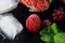 Macro frozen raspberry, blackberry, strawberries mint leaves, pieces of ice on a black shale board, frozen fruit, set