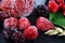 Macro frozen raspberry, blackberry, strawberries mint leaves, pieces of ice on a black shale board, frozen fruit, set