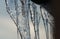 Macro icicles forming from roof. Crystal closeup details of icicle background. The beginning of the warm season, the end of winter