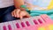 Macro little girl finger gambols on pink piano keyboard