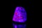 Macro mineral stone ruby under ultraviolet light on a black background