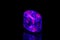 Macro mineral stone ruby under ultraviolet light on a black background