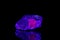 Macro mineral stone ruby under ultraviolet light on a black background