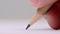 Macro of pencil writing or drawing. Unknown person drawing line or letter on white paper.